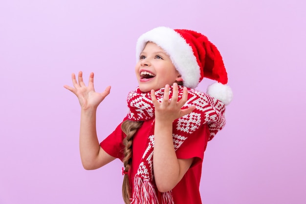 A very joyful little girl in a New Year's hat and a red warm scarf.