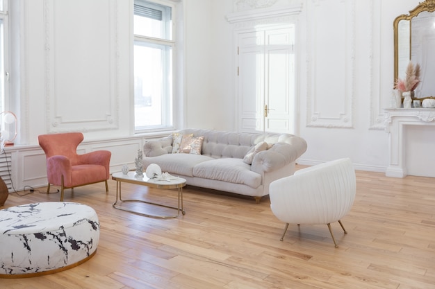 Very light baroque style luxury interior of big sitting room. White walls decorated with awesome stucco. Royal style apartment with chic furniture with gold elements