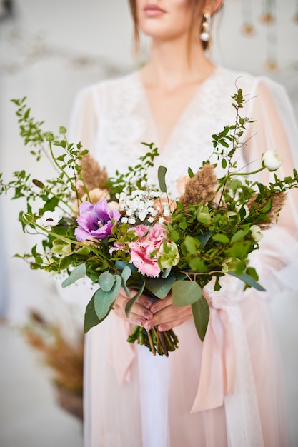 Foto giovane donna molto piacevole che tiene il grande e bello mazzo variopinto di nozze del fiore. mattina sposa