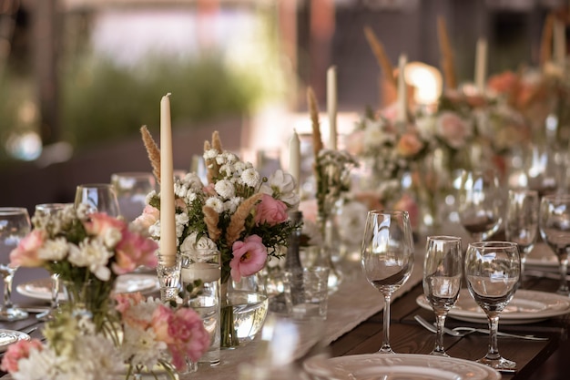 Foto un tavolo di nozze molto ben decorato con un bellissimo arredamento con piatti e tovaglioli nel giardino primaverile. bellissimi fiori sul tavolo nel giorno del matrimonio. la tavola elegante.