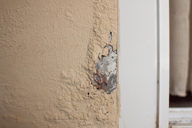 Very old falling apart wall crumbling stucco coating and\
falling off paint the wall is cracked