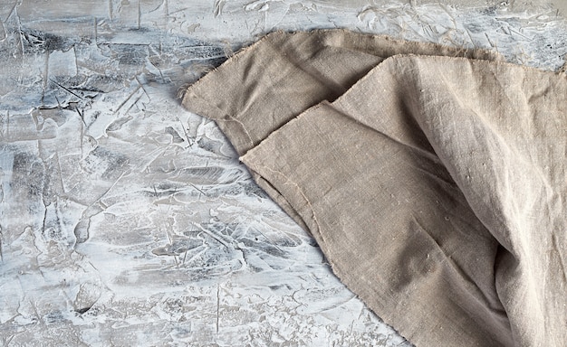 Очень старое серое винтажное кухонное полотенце на сером цементном фоне