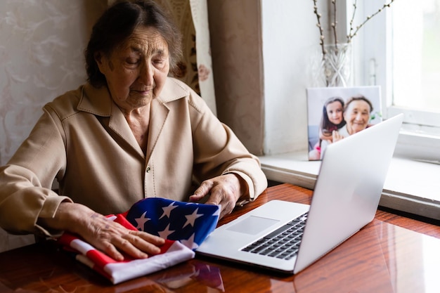 very old senior woman with laptop and usa flag.