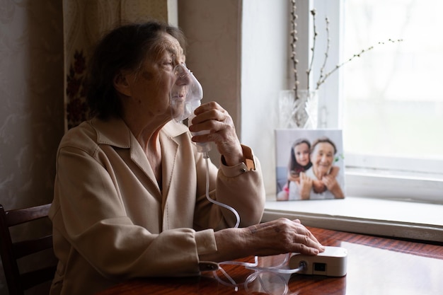 very old woman and nebulizer. Woman making inhalation.