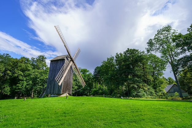 Very old wooden windmill on green grass meadow.