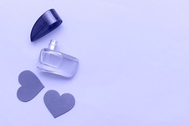 Very Peri color of the year 2022 Perfume bottle as gift and red hearts on a pink background