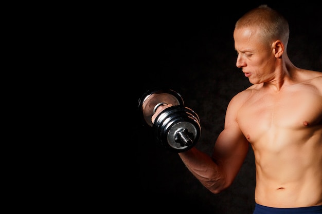 Very power athletic guy , execute exercise with dumbbells, on dark background
