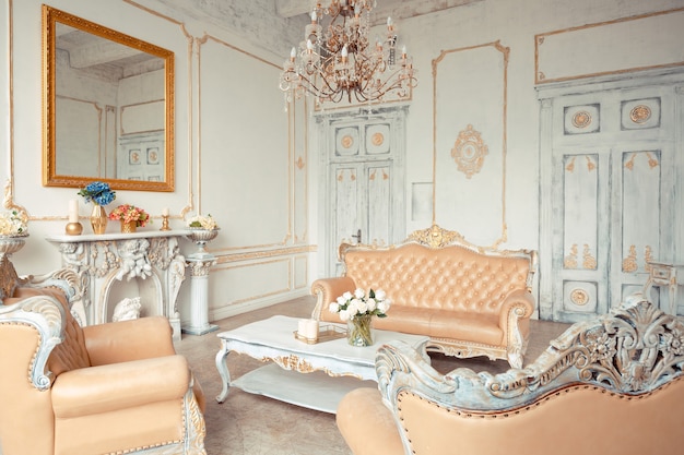 Very rich interior of the apartment with golden decorations on the walls in the Baroque style and luxury furniture with gold paint.