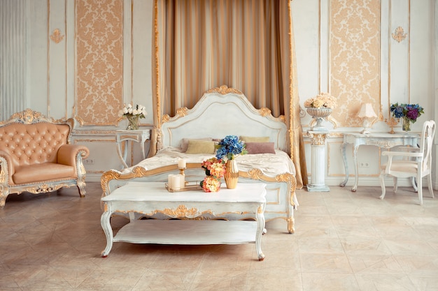 Very rich interior of the apartment with golden decorations on the walls in the Baroque style and luxury furniture with gold paint.