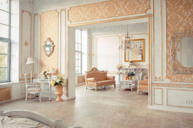 Very rich interior of the apartment with golden decorations on the walls in the Baroque style and luxury furniture with gold paint.