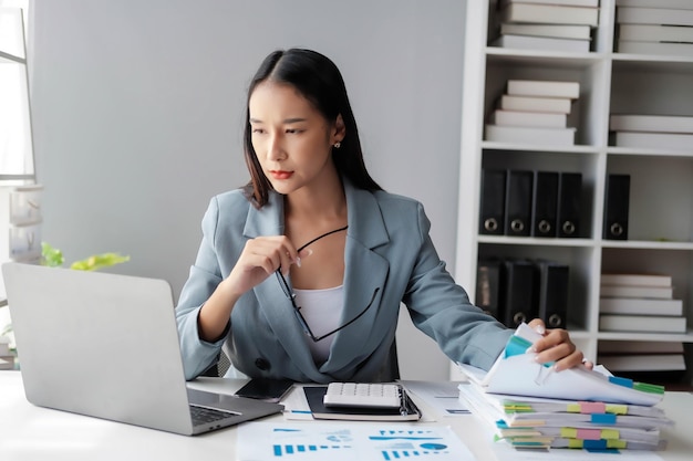 パソコンの前に座って書類の積み重ねを見ている非常にストレスを感じているビジネス女性 アジアの女性はラップトップで働いている間ストレスを受けています 仕事で病気を感じています コピースペース