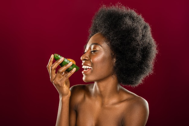Очень вкусно. Довольная жизнерадостная женщина смотрит на авокадо, готовясь его съесть