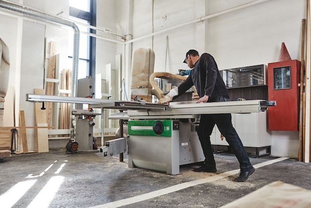 Verzagen van een houten plank op een schuiftafelzaag Houtbewerking en timmerwerkproductie