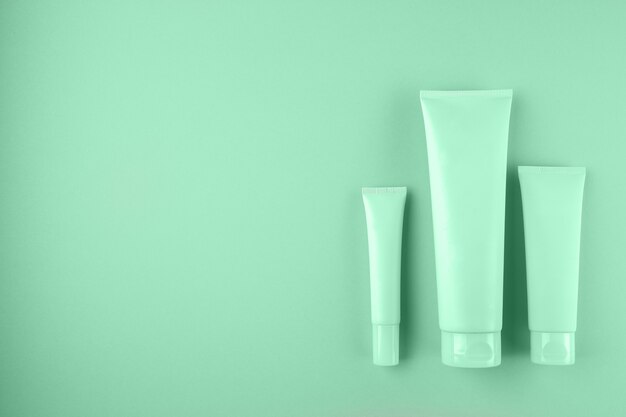 Verzameling van drie cosmetische buizen op mint kleur