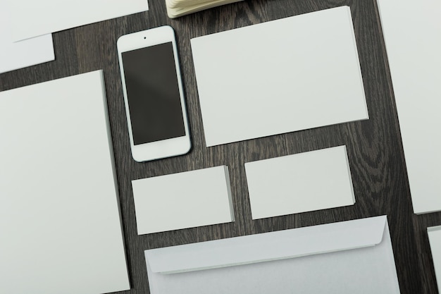 Verzameling van lege schrijfwaren en een smartphone op een houten oppervlak voor creatieve ontwerpideeën en kantoororganisatie