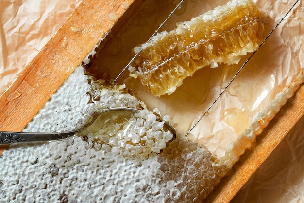 Verzegelde honingraat van honing in een houten frame met houten lepel voor het mengen en proeven van natuurlijke honing