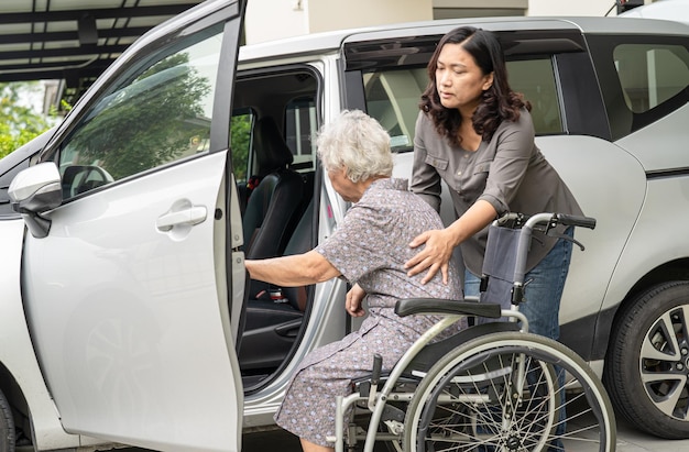 Verzorger dochter helpt en ondersteunt aziatische senior of oudere oude dame vrouw patiënt bereidt zich voor om naar haar auto te gaan.