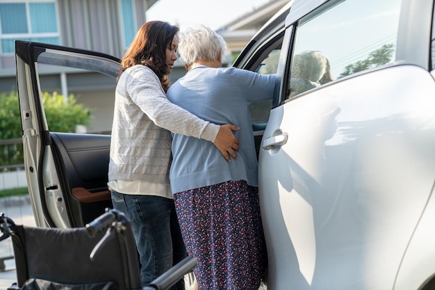 Verzorger helpt Aziatische senior of oudere oude dame vrouwelijke patiënt om naar haar auto te gaan, gezond sterk medisch concept