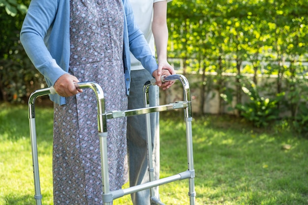 Verzorger hulp en zorg Aziatische senior of oudere oude dame vrouw gebruikt rollator met een sterke gezondheid tijdens het wandelen in het park in een fijne frisse vakantie