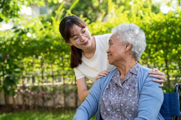 Verzorger hulp en zorg Aziatische senior of oudere oude dame vrouw patiënt zittend en gelukkig op rolstoel in park gezond sterk medisch concept