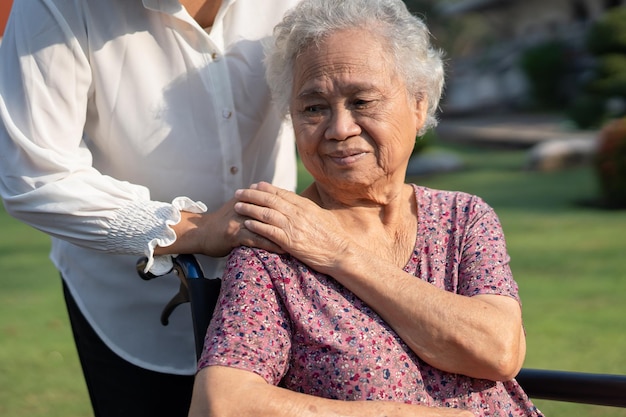 Verzorger hulp en zorg Aziatische senior of oudere oude dame vrouw patiënt zittend op rolstoel in park gezond sterk medisch concept