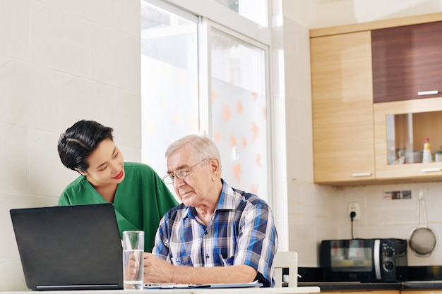 Verzorger senior man helpen met computergebruik