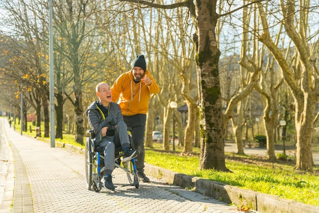 Verzorger wijst vooruit en praat met een gehandicapte man in een park