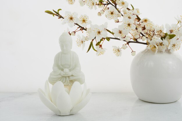 Statua del buddha di compleanno del buddha vesak wesak con ciliegia in fiore su sfondo bianco rituale termale