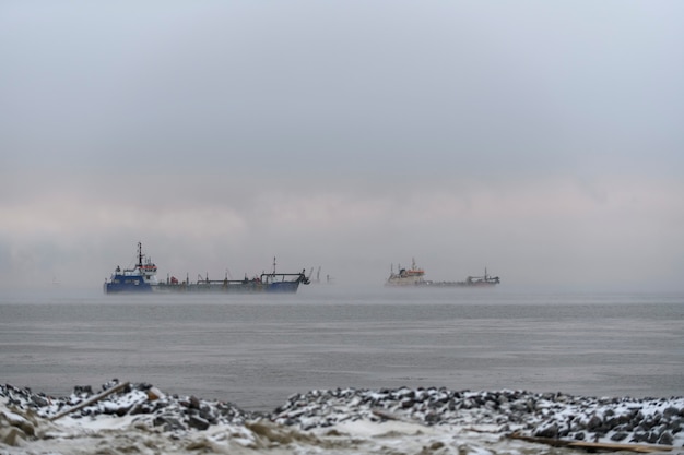 Vessel engaged in dredging at sunset time. Hopper dredger working at sea. Ship excavating material from a water environment.