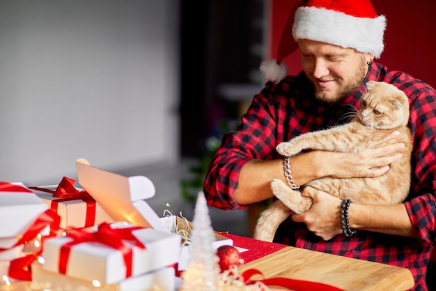 Vet Man in Santa hat and cat in hand making greeting card for New Year and Christmas