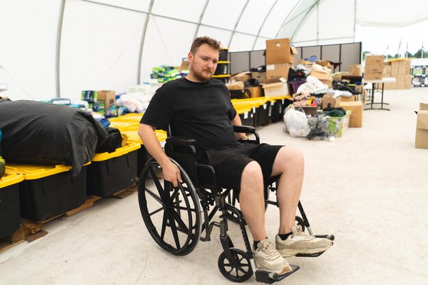 Ветеран-инвалид в инвалидной коляске помогает в гуманитарном подразделении по поддержке жертв войны
