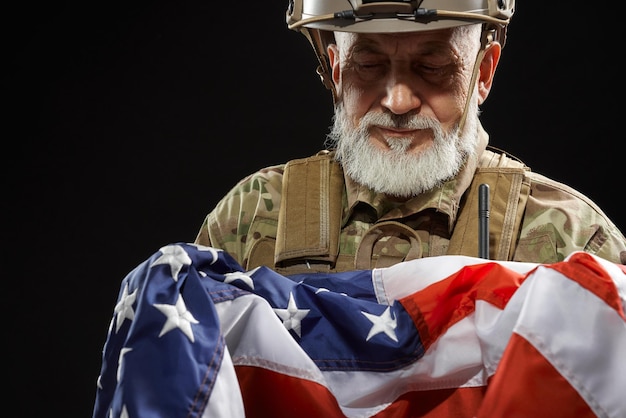 Photo veteran in military uniform holding american flag