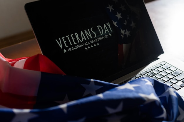 Veterans day written in laptop with flag of the United States, on a rustic wooden background