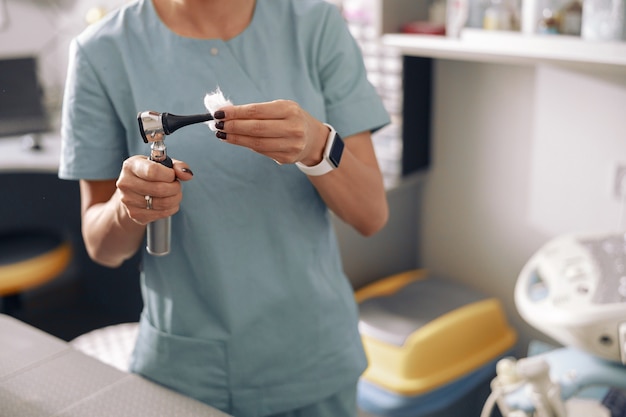 Veterinarian cleans otoscope after exanining patient in light office of clinic closeup