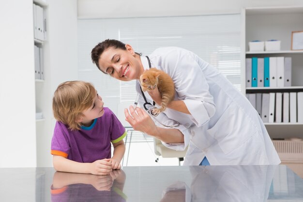 Veterinarian doing injection at a cat with its owner 