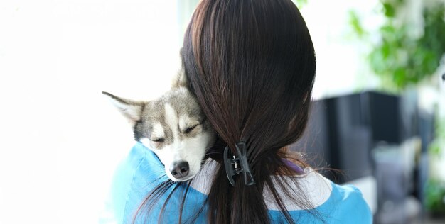 医は可愛い眠っているハスキー犬を腕に抱いている