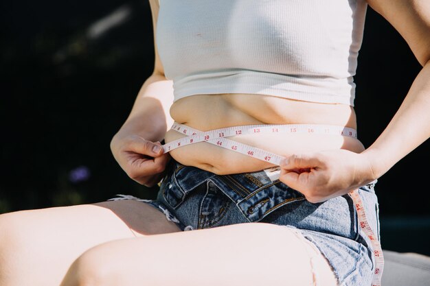 Vette vrouw dikke buik mollige obese vrouw hand die overmatig buikvet vasthoudt met meetband vrouw dieet levensstijl concept