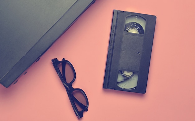 Photo vhs player, video cassette, 3d glasses on a pink surface