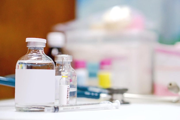 Vial and Ampule of Drugs with Plastic Syringe on white table and blurred background.