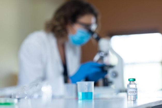 Vial bottle with Covid-19 text on table in laboratory