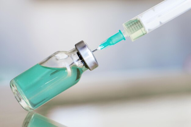 Vial filled with liquid vaccine in medical lab with syringe medical ampoule