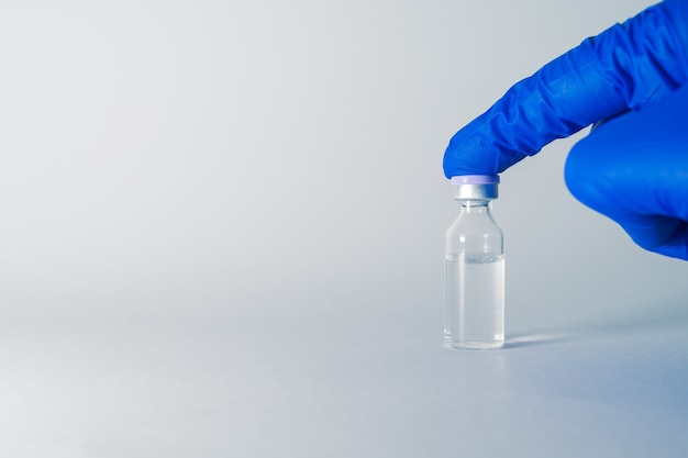 Vial of medicine for injection in doctors hand medical glass vial for vaccination flu vaccine taken isolated from a white background