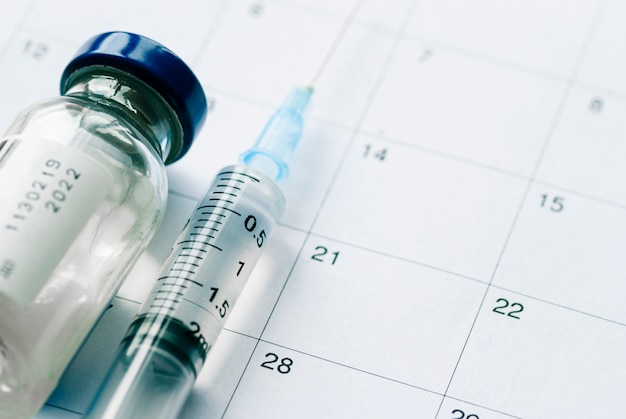 The vial with vaccine and syringe on calendar