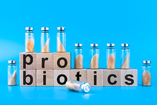 Vials, ampoules with dry probiotic, bifidobacteria, with probiotic powder inside on a blue background. Copy space.