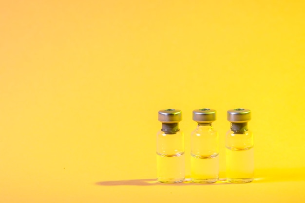 Photo vials of vaccine on yellow surface