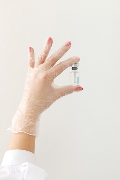 Vials with serum in hand in a medical glove