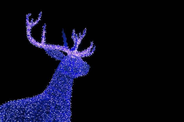 Яркие синие освещенные рождественские олени в форме уличных украшений на темном фоне