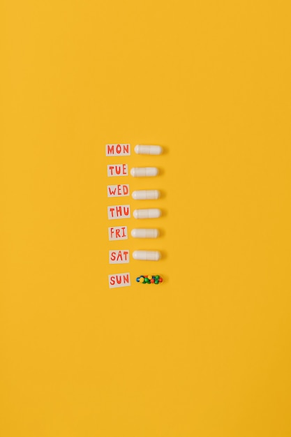 黄色の背景に砂糖菓子をまぶした薬の丸薬カプセルの鮮やかなカラフルなフラットレイ。過剰摂取の薬の使用と栄養補助食品への依存症の創造的な概念。