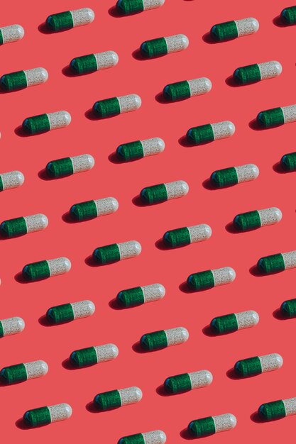 Photo vibrant colorful pattern of green gelatine medicine pill capsules on red background.