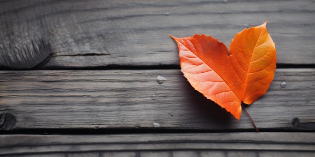 Photo vibrant orange autumn leaf on weathered wooden surface captures the essence of fall